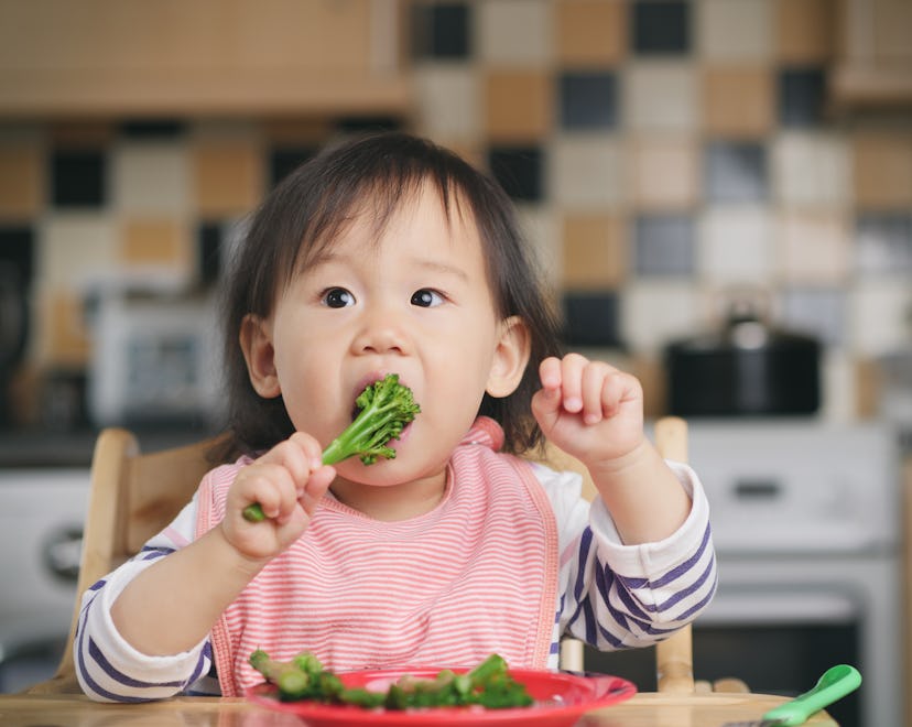 a baby eating broccoli in an article about baby led weaning, what is baby-led weaning, how to start,...