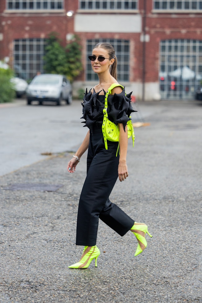 MILAN, ITALY - SEPTEMBER 24: Nina Sandbech wears black off shoulder top, black pants, neon green Bal...