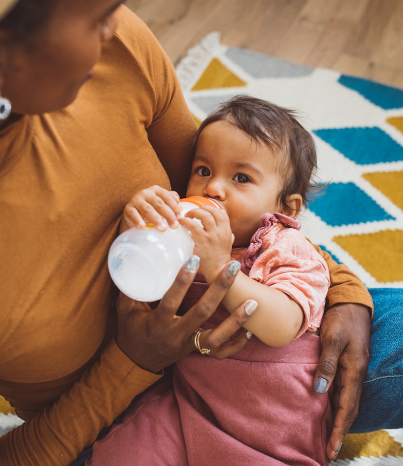 Young mother feeding baby girl in living room, what to do if baby drinks spoiled breast milk