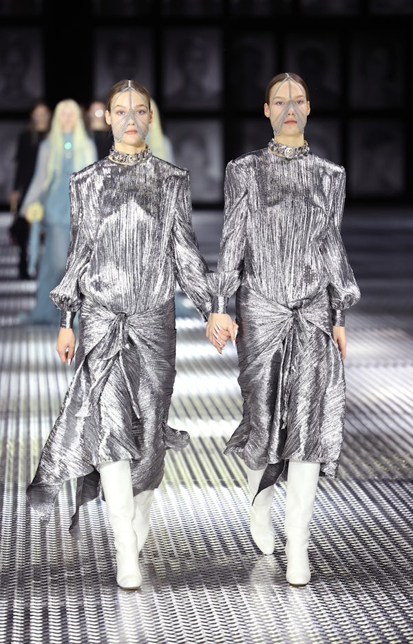 Models wear statement silver dresses on Gucci's Twinsburg Show during Milan Fashion Week.