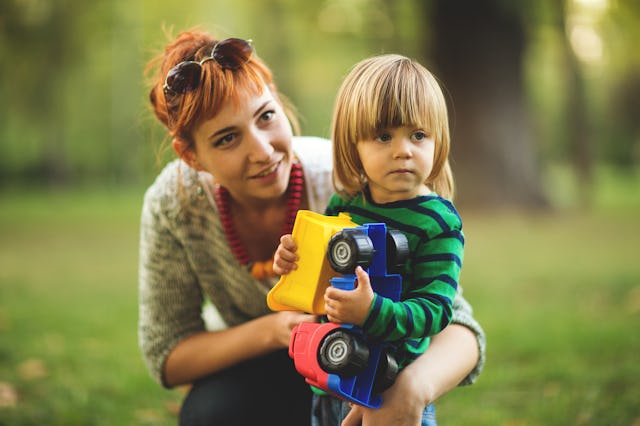 Young woman and boy playing with truck toy and in the park,front view