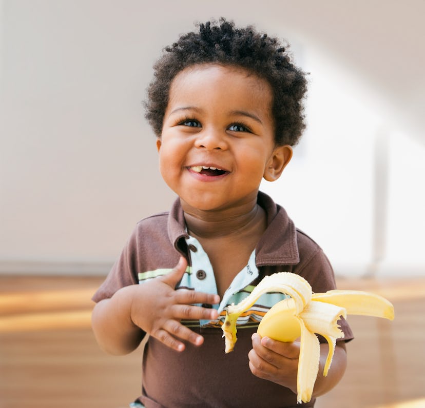 baby eating a banana in a way that is in sync with the baby-led weaning approach to infant feeding