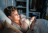 Young woman using smartphone on the bed in an article of up in the middle of the night instagram cap...