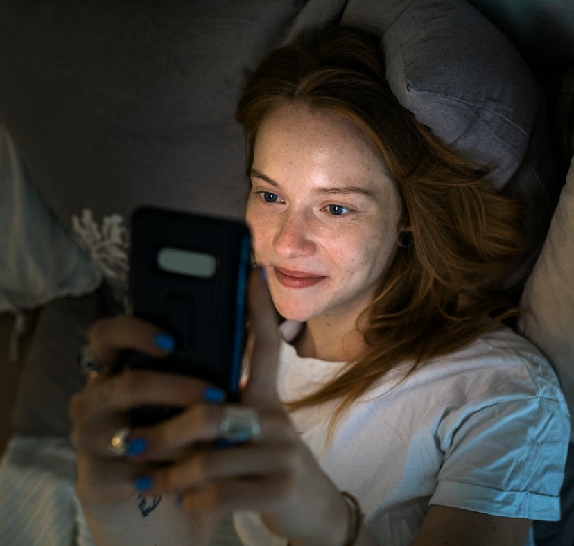 Gen Z woman sending her partner a sexy text message before bed.