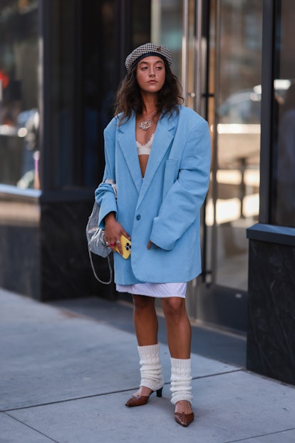 A fashion week guest in an oversized blazer and leg warmers at New York Fashion Week.