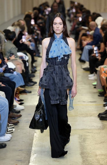 A model walking the runway in a blue dress with a light blue bow tie at the Burberry show during Lon...