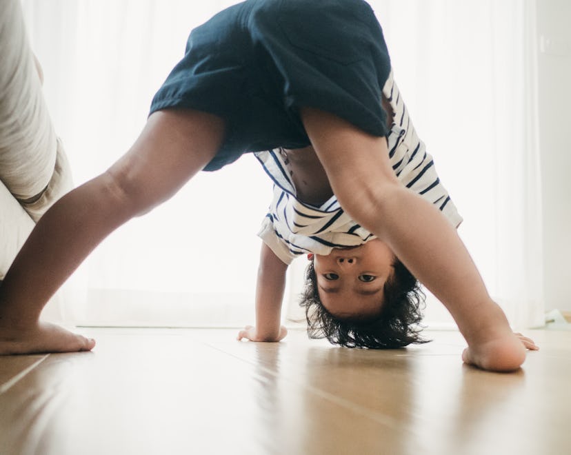 Asian baby boy playing in living room at home, toddler standing on his head