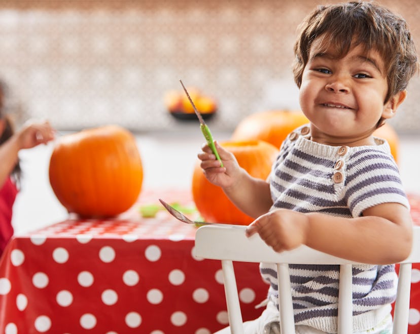 Kid holding knife while carving pumpkins