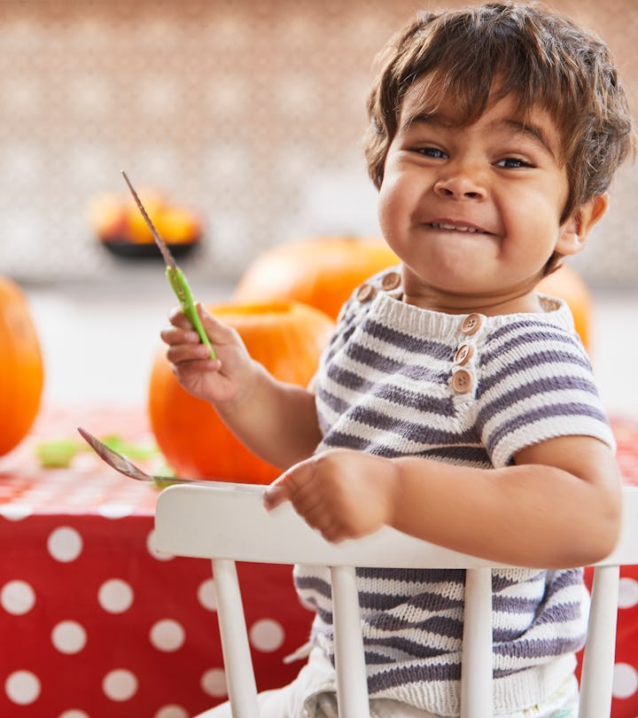 Kid holding knife while carving pumpkins