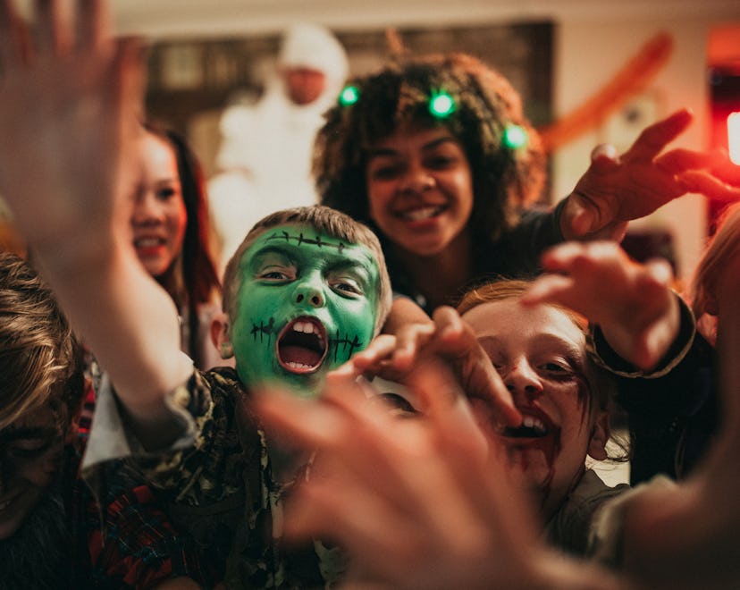 Group of young friends dressed in costumes reaching out towards the camera like zombies.