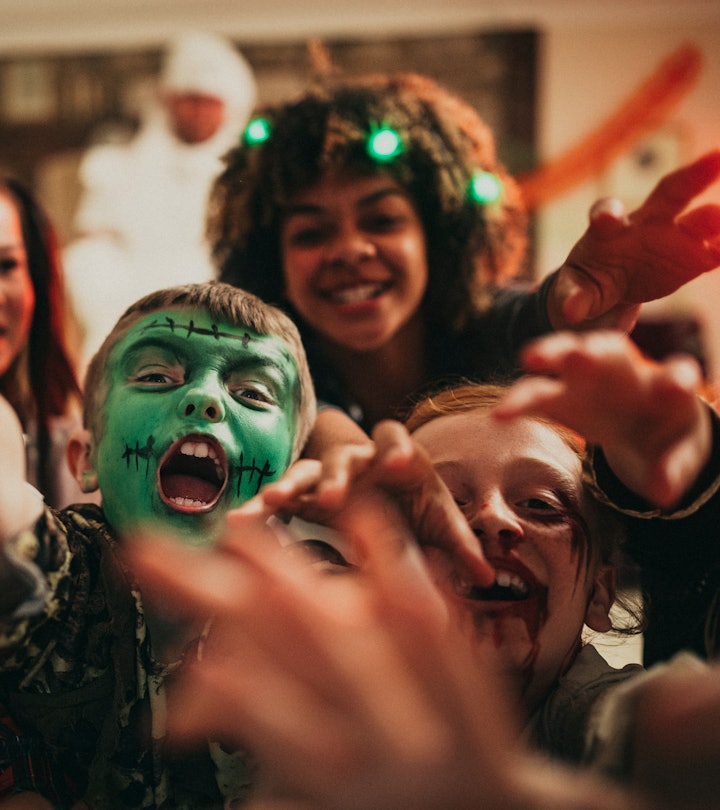 Group of young friends dressed in costumes reaching out towards the camera like zombies.