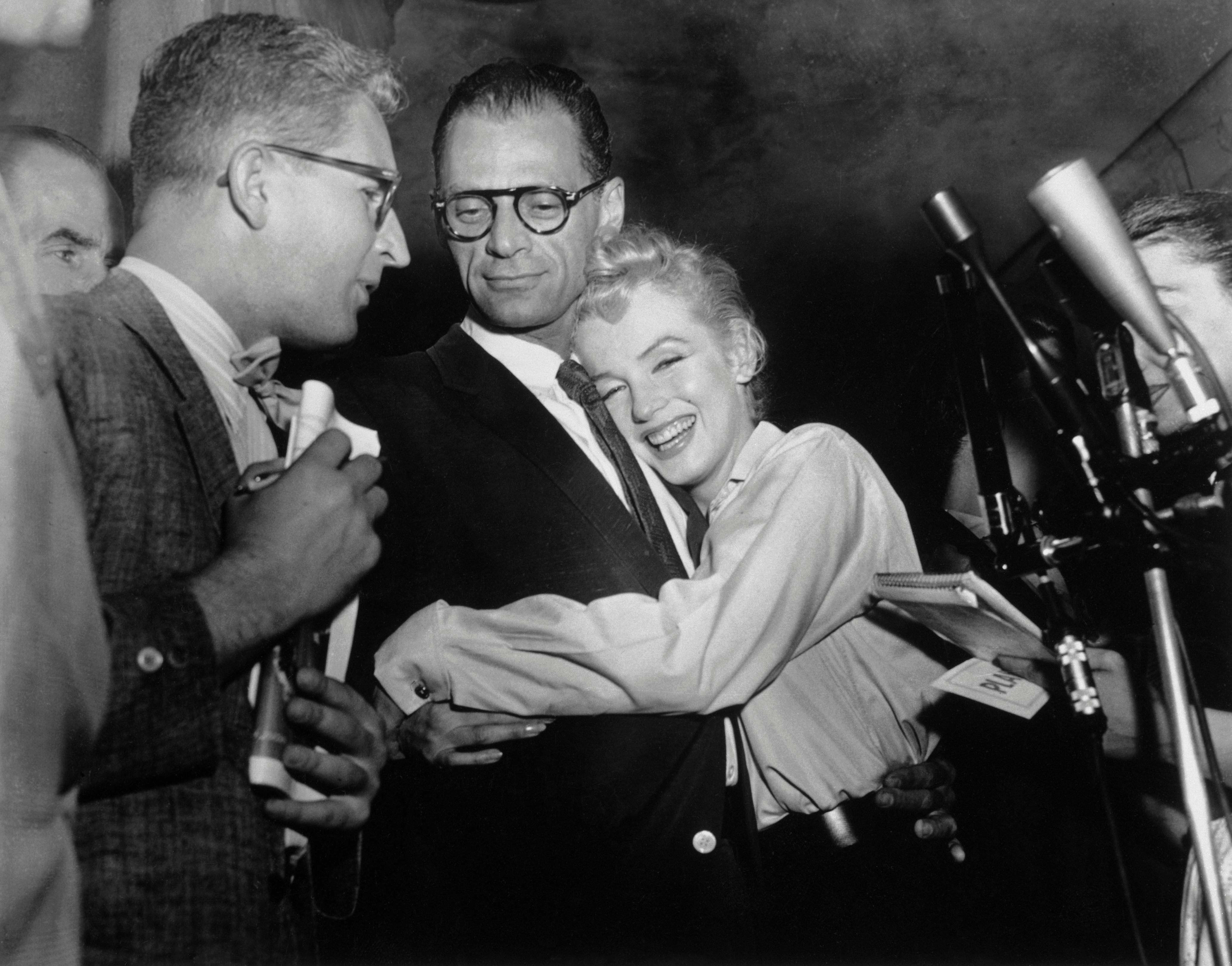 (Original Caption) Actress Marilyn Monroe hugs playwright Arthur Miller as an unidentified reporter ...