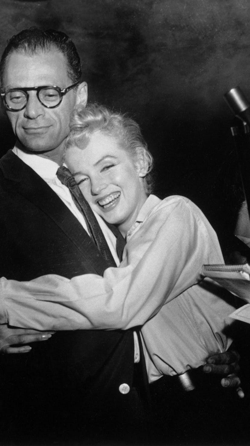 (Original Caption) Actress Marilyn Monroe hugs playwright Arthur Miller as an unidentified reporter ...