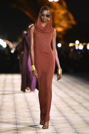 A model wearing a St. Laurent hoodie maxi, tight, burgundy dress styled with black sunglasses at the...