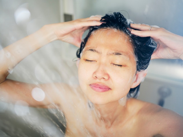 A young Japanese woman relaxing in a warm shower in an article about how much hair loss is normal