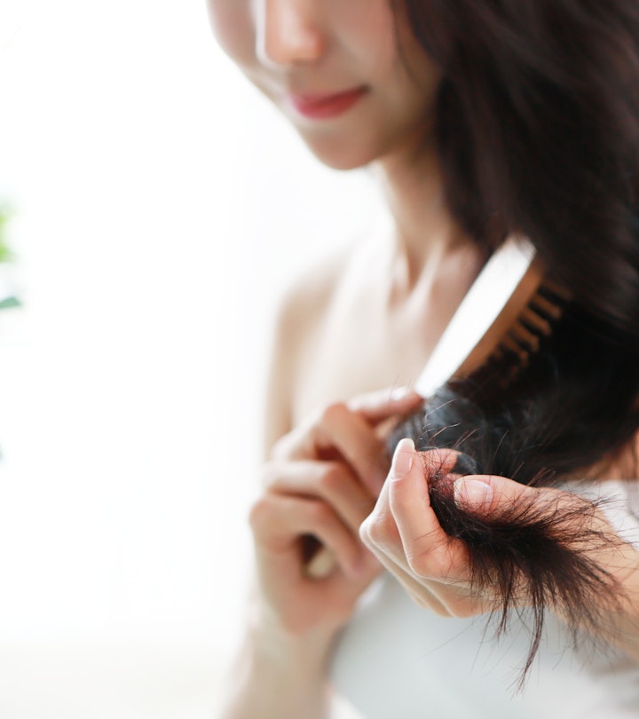 a woman brushing her long, dark hair in an article about how much hair loss is normal and how to kno...