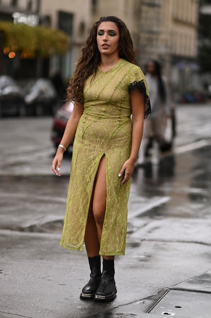 A guest is seen wearing a green sheer dress and black boots outside the Koche show during Paris Fash...
