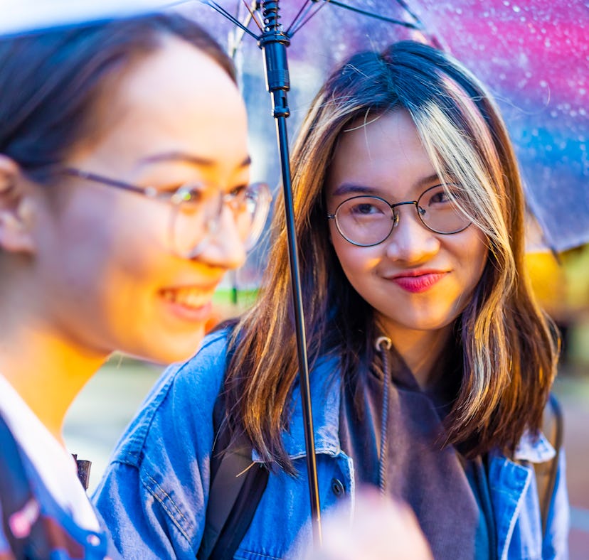 young people who learned how to style your hair in humidity standing outside under an umbrella.