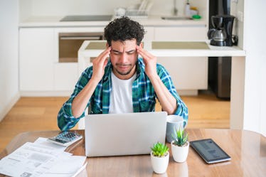 A stressed out guy works on his laptop at home