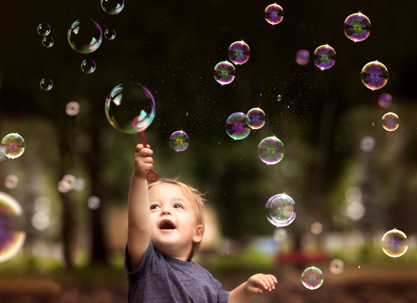 An image of a 2 year old toddler holding a bubble wand  in an article about boy names that start wit...