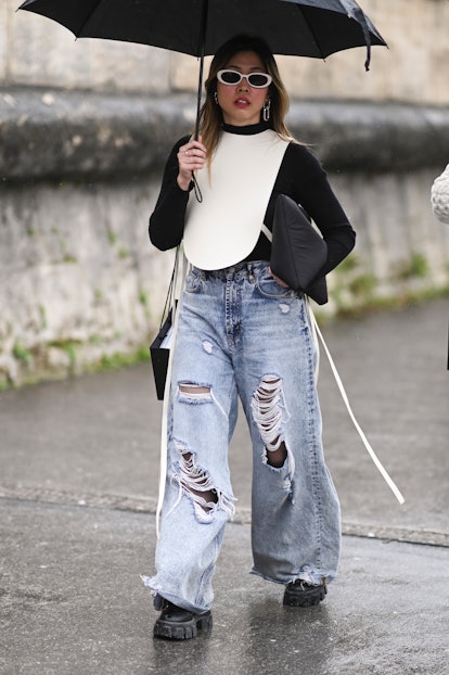 A guest is seen wearing a black and white top and blue shredded jeans outside the Dior show during P...
