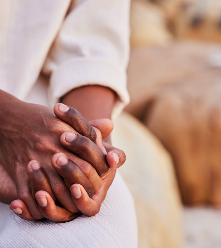 Close-up of an African couple holding hands while sitting together on a beach at sunset