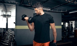 A man doing bicep curls with dumbbells at a gym.