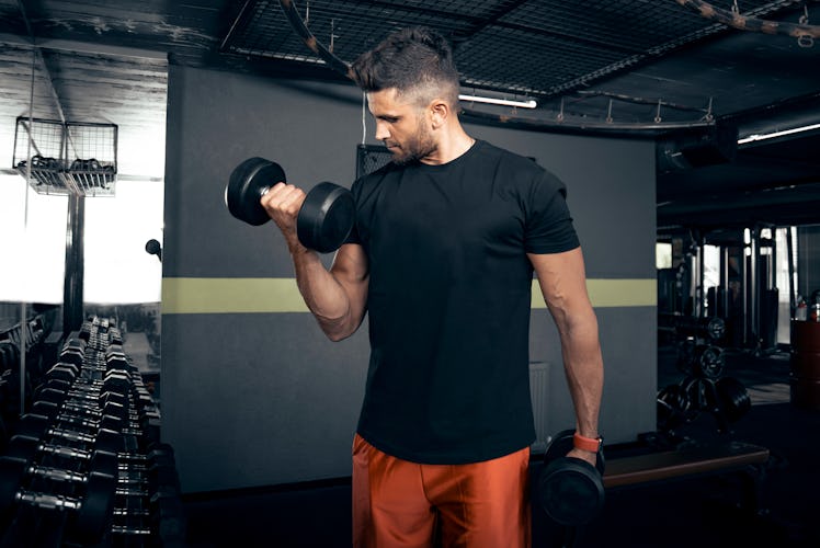 A man doing bicep curls with dumbbells at a gym.