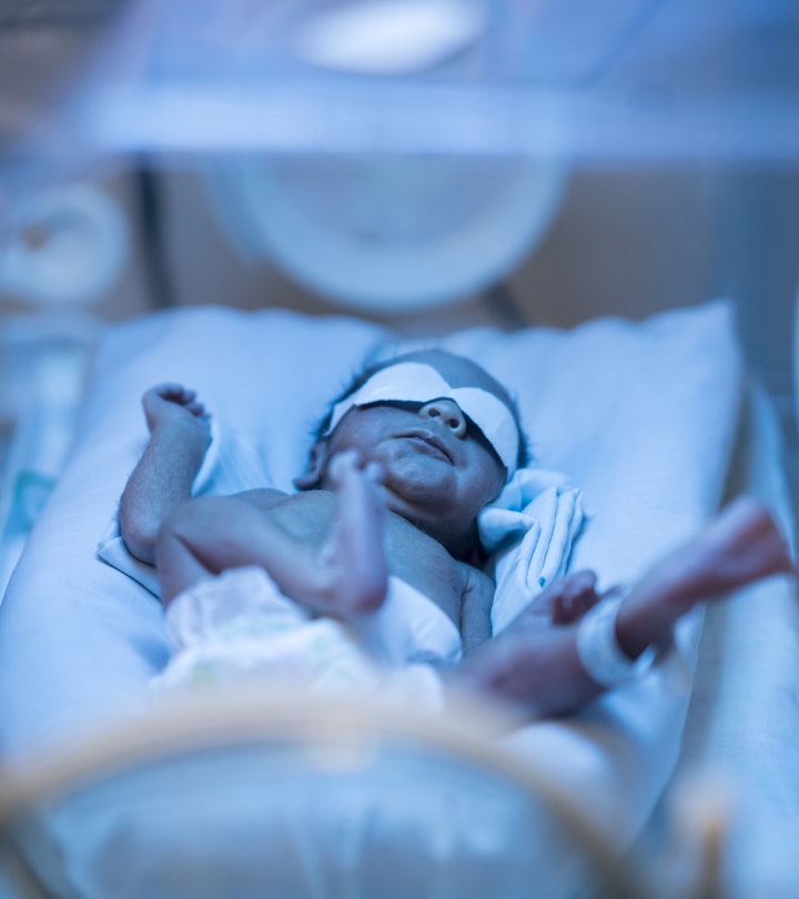 Newborn baby alone in the NICU incubator getting treated for jaundice under ultravioleght light.