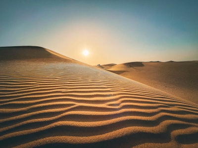 A close-up of desert dunes with a sunset in the background