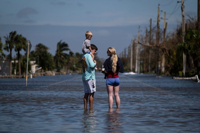 A family stand on a flooded street in the aftermath of Hurricane Ian.
