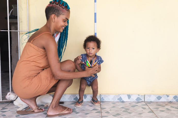 Mother measuring her baby boy's height against wall