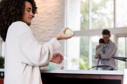 The new mom prepares a bottle with milk by shaking it with breast milk and formula.