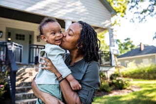 Mother holding toddler in front of new home