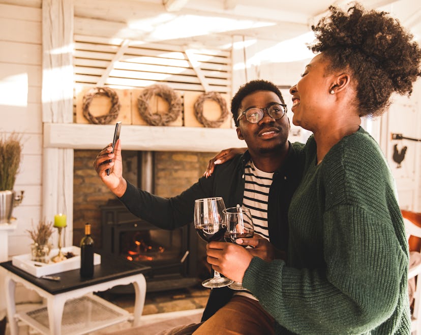young couple taking selfies while enjoying red wine
