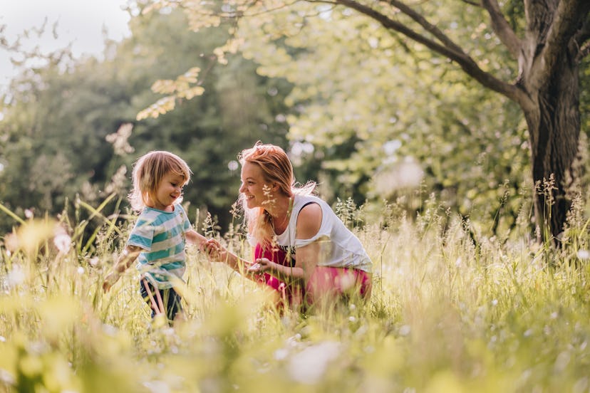 nanny playing with a toddler out in a meadow in an article about how to get a kid used to a new nann...