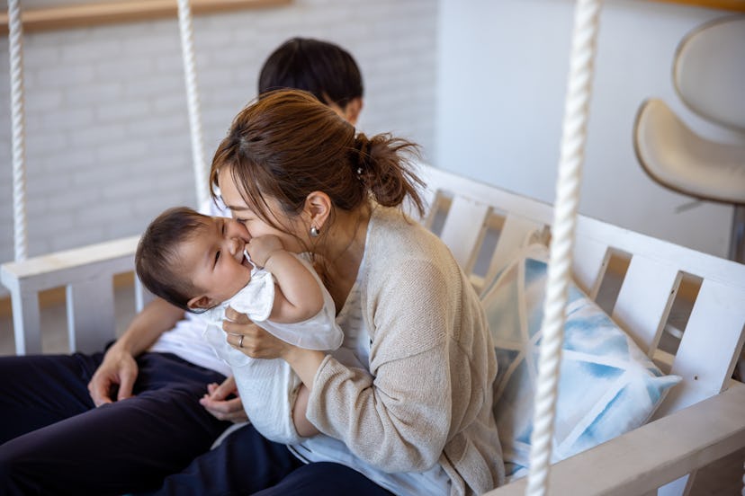 Mom gives baby kissse while dad is in the background in an article about baby names that start with ...