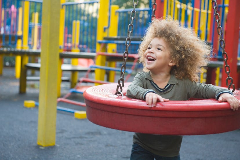 Child playing and thriving using tire swing set in the playground.