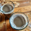 Freshly brewed warm milk coffee is served in a clear glass with a blur background