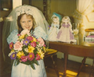 Cute child playing dress up, little girl dressed as bride. Conceptual image for daydreaming, anticip...