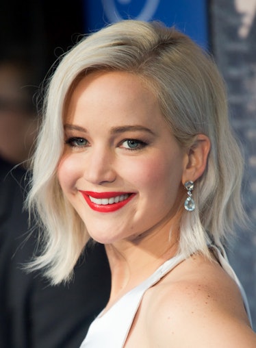 Jennifer Lawrence at red carpet event with icy blonde hair, red lips, and full makeup glam