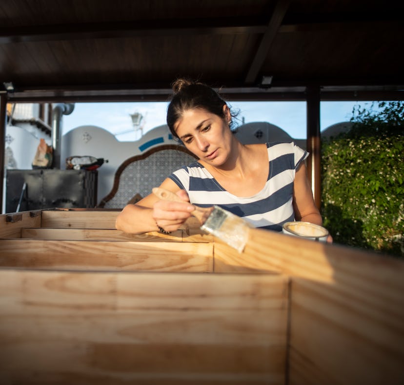 Woman varnishing and painting the renovated furniture of her house