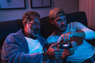Special Family Moments - Close up of father and son enjoying evening at home and playing video games...