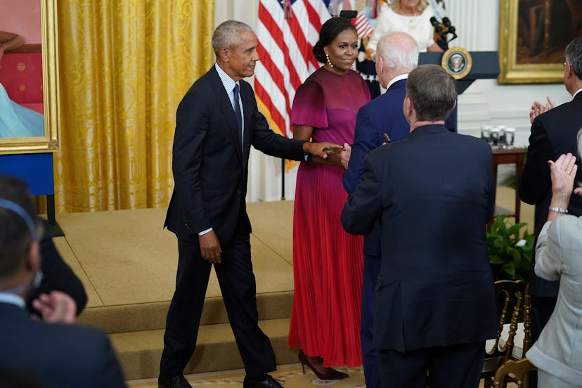 Former US president Barack Obama and wife Michelle Obama walk past President Joe Biden to take their...