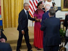 Former US president Barack Obama and wife Michelle Obama walk past President Joe Biden to take their...