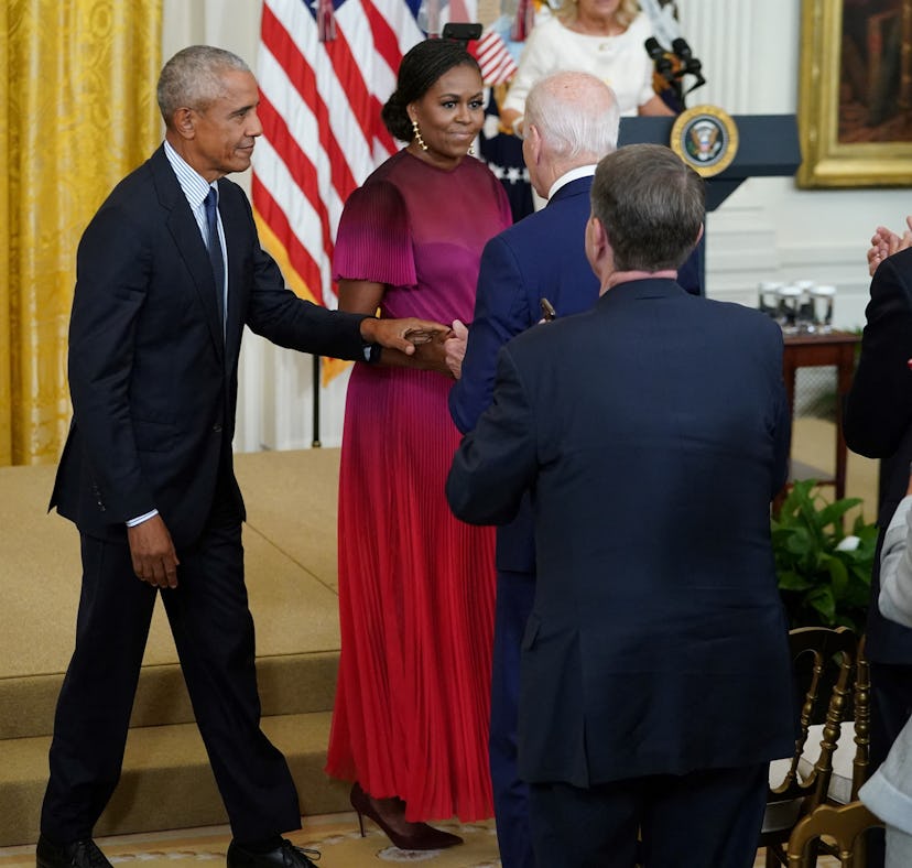 Former US president Barack Obama and wife Michelle Obama walk past President Joe Biden to take their...