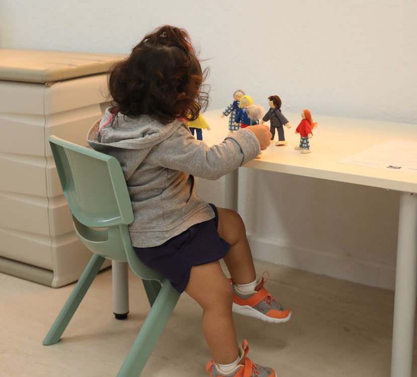 A young girl playing with toy dolls in Spain.