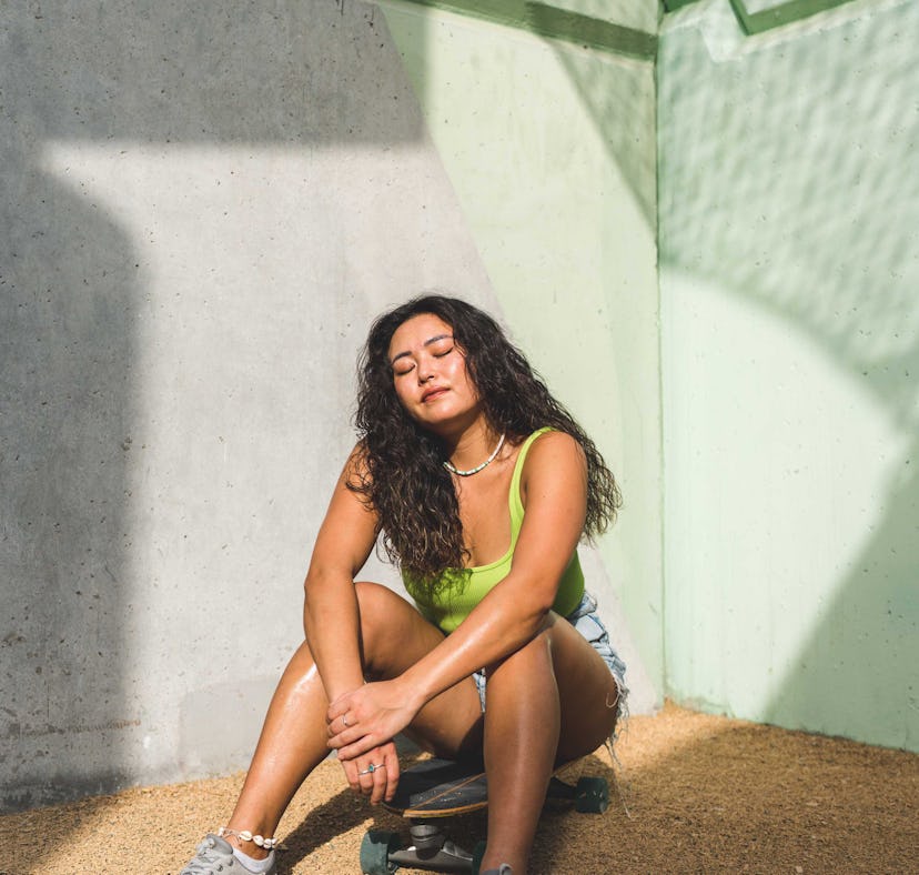 young woman sits down outside with her eyes closed as she reflects on her september 12, 2022 weekly ...