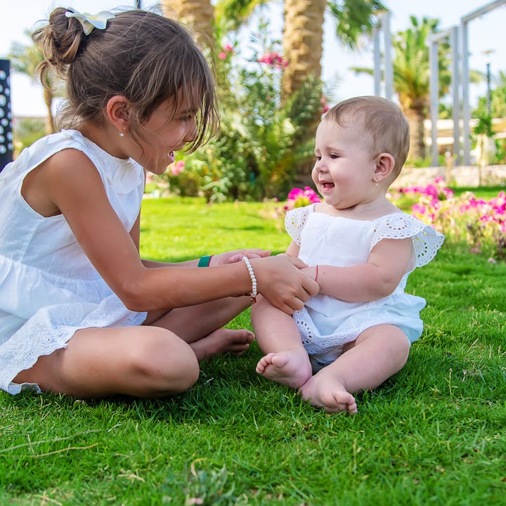 The girl's children are sitting under a palm tree. Selective focus. Nature.