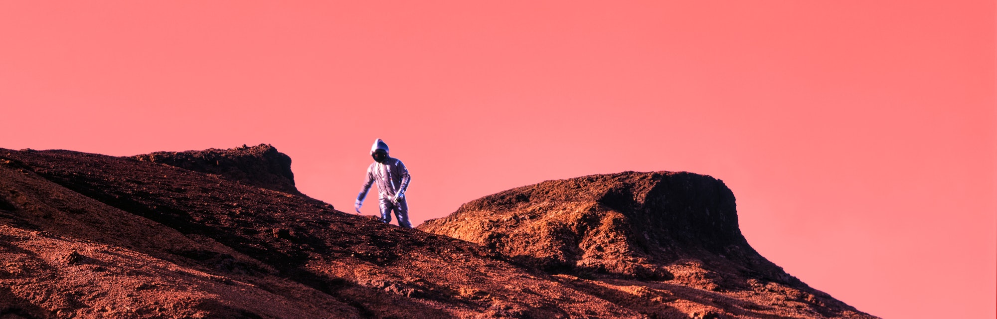 Astronaut walking on red Mars rock